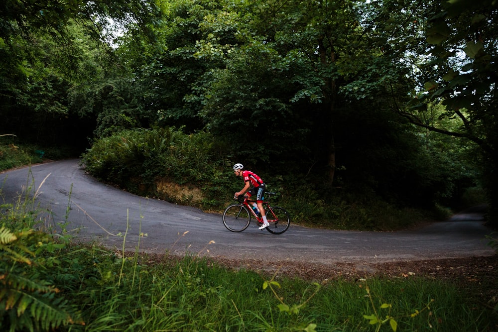 man in red shirt riding bicycle on road during daytime