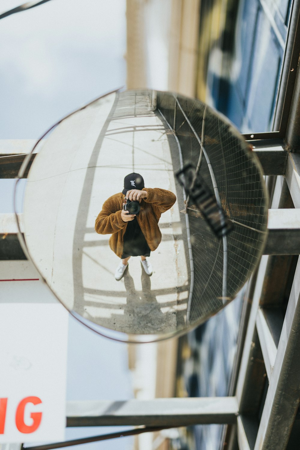 man in brown jacket and blue denim jeans sitting on round glass ball