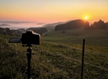 A scenic outdoor shot showing a camera on a tripod during golden hour.