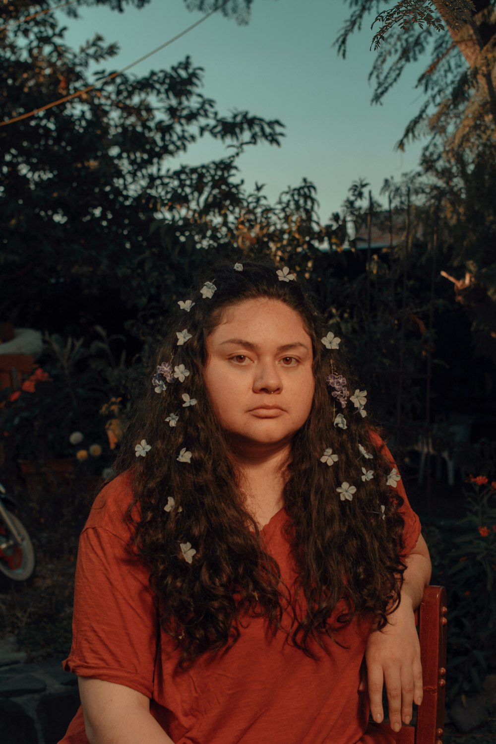 woman in orange shirt standing near green tree during daytime