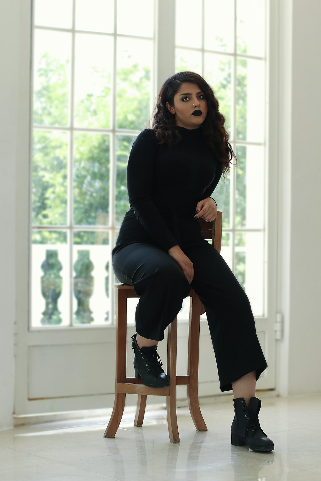 woman in black long sleeve shirt and black pants sitting on brown wooden chair