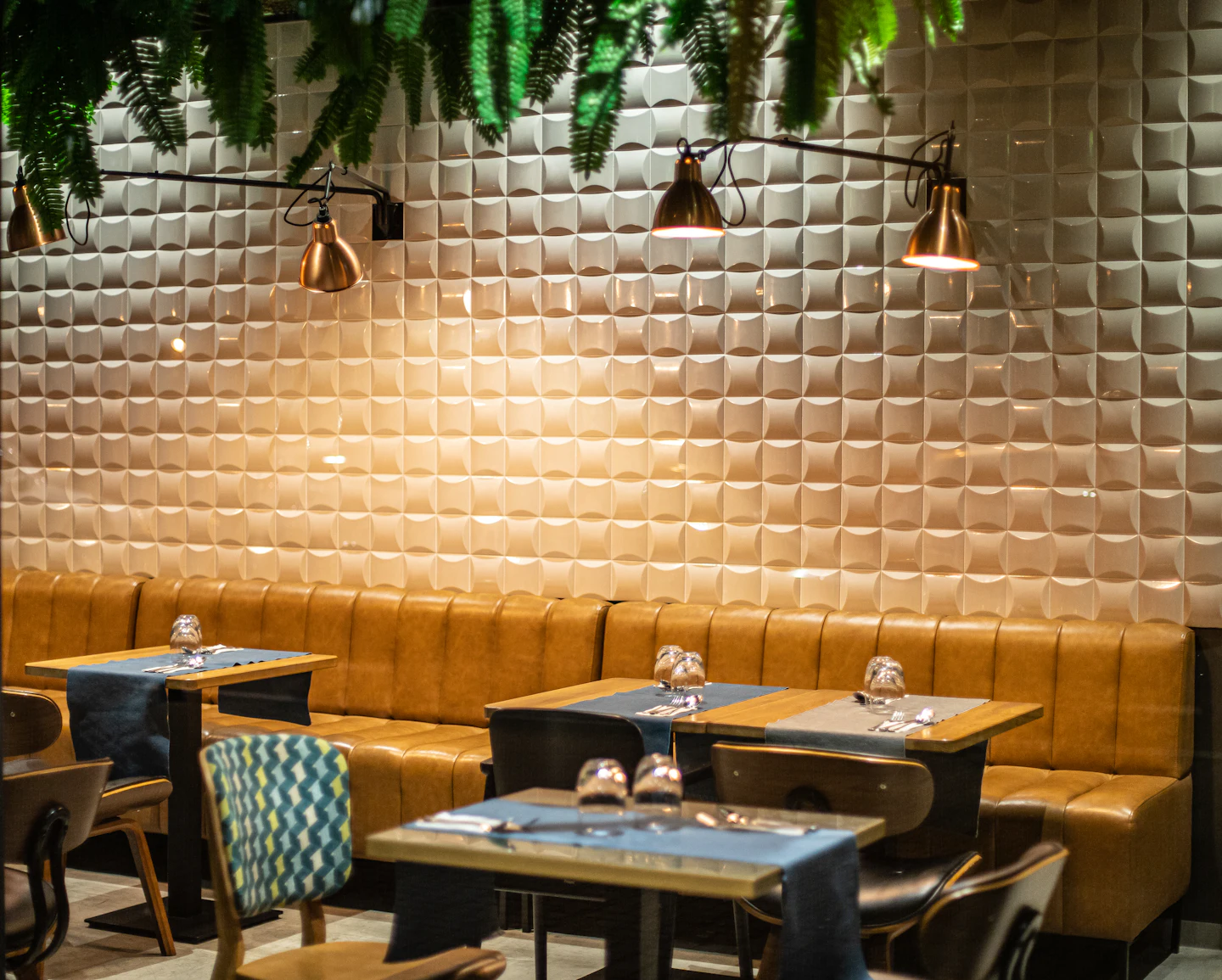Banquette en cuir sous des appliques murales, mur texturé éclairé en lumière rasante
