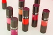 Collection of colorful lipsticks and blushes arranged on a wooden table