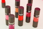 Collection of colorful lipsticks and blushes arranged on a wooden table
