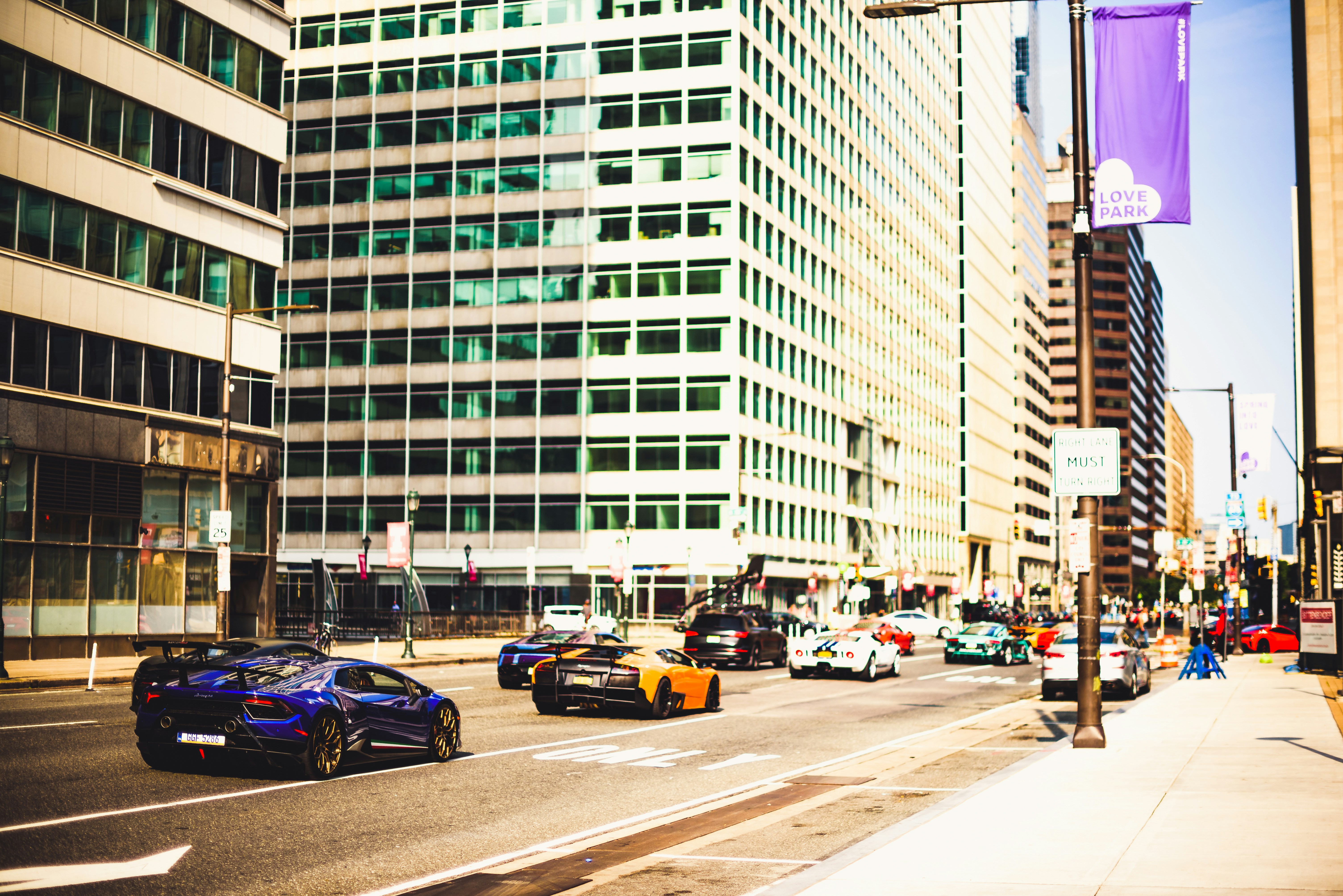 cars parked on side of the road near high rise buildings during daytime