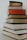 A stack of books with vibrant covers set against a simple black and white backdrop.