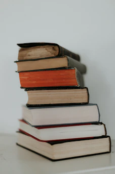 Stack of Walton Weaver’s books with gold and navy covers on a white wooden table