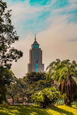 brown concrete building near green trees under blue sky during daytime