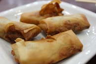 Golden crispy spring rolls arranged neatly on a rustic wooden board.