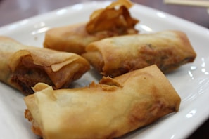 Golden crispy spring rolls arranged neatly on a rustic wooden platter.