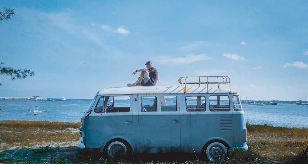 woman in white tank top sitting on blue and white van during daytime