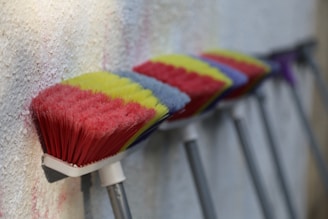 Finished colorful brooms hanging neatly in the workshop.