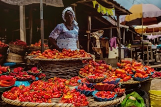 man in white long sleeve shirt and white hat standing in front of fruit stand