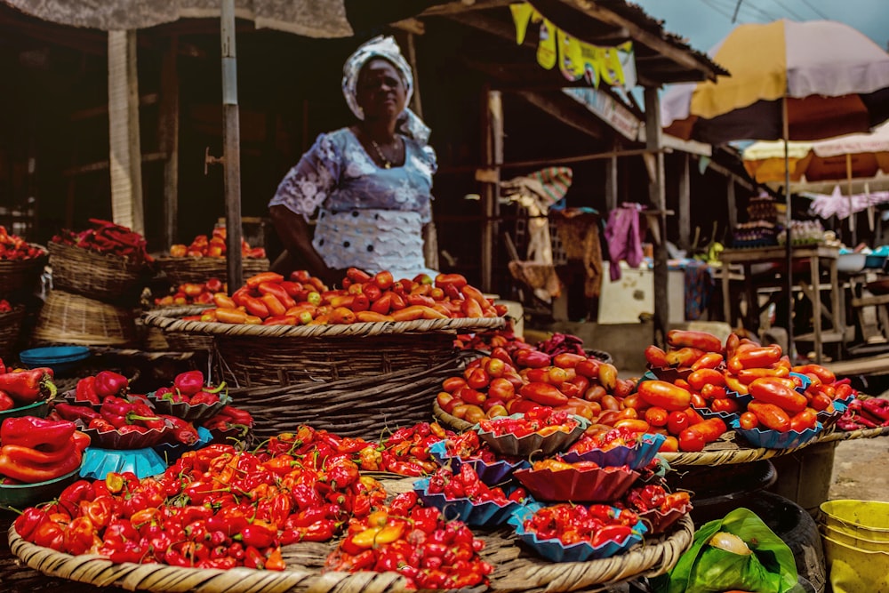 man in white long sleeve shirt and white hat standing in front of fruit stand