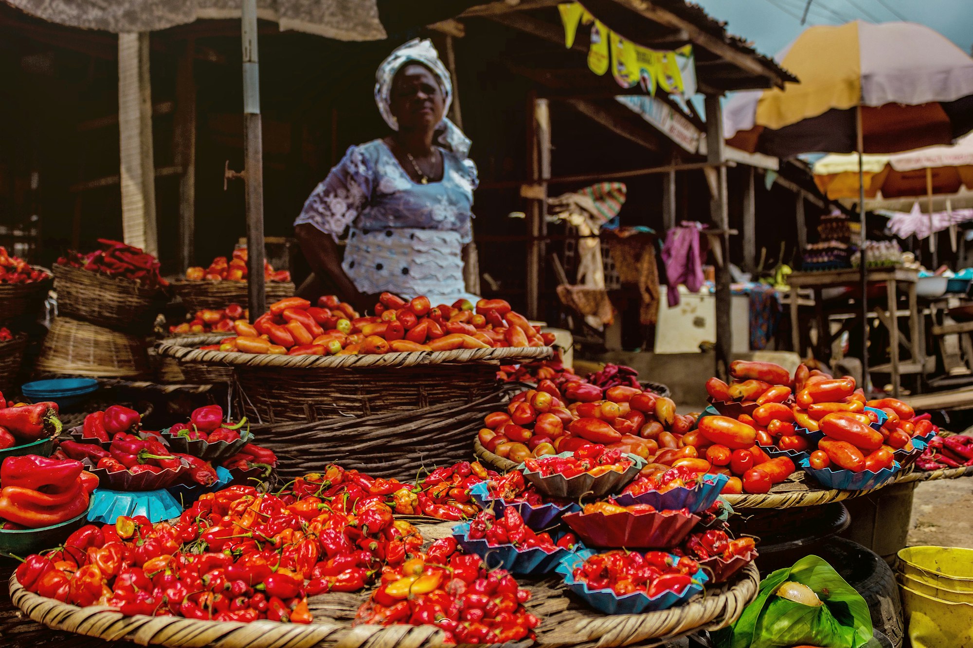 Woman selling pepper sits over her wares in a market.