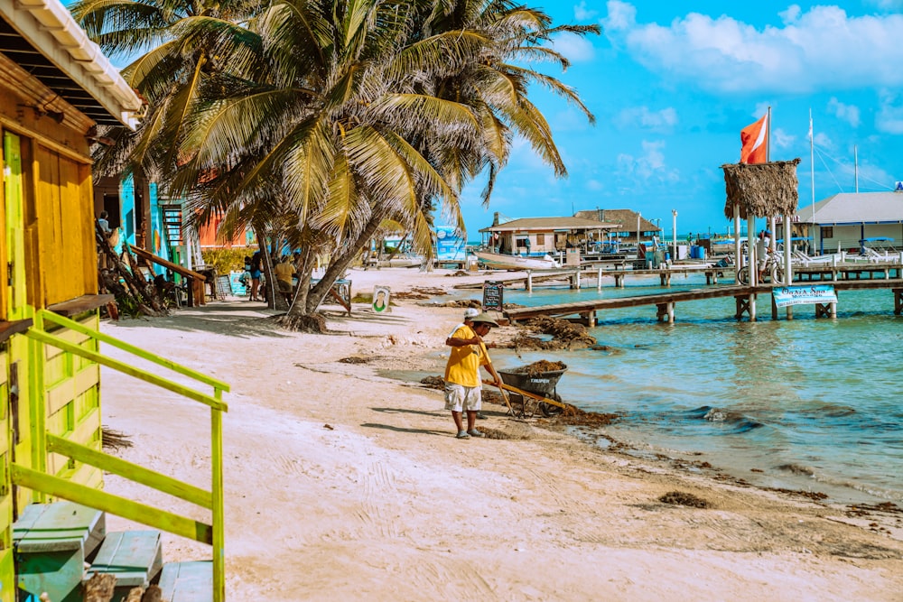 man in yellow shirt and black shorts walking on beach during daytime