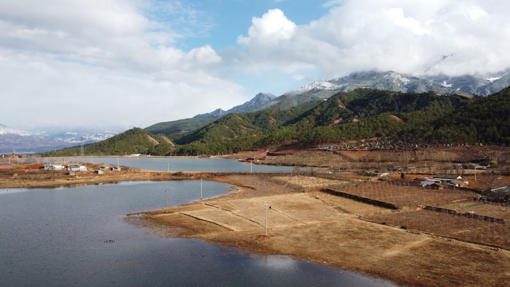 green mountain beside body of water under cloudy sky during daytime