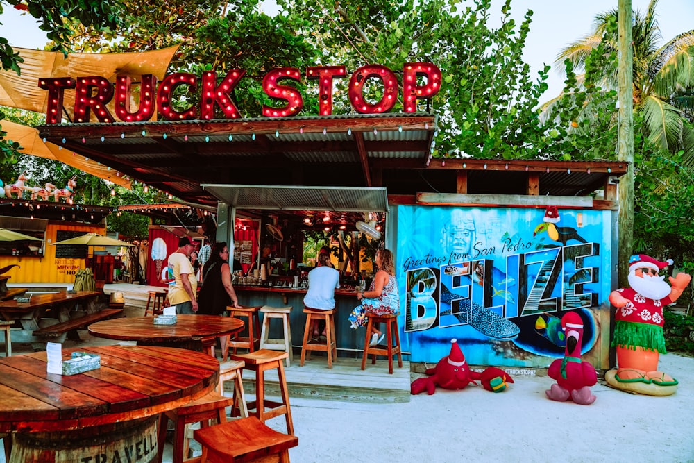 people sitting on brown wooden chairs near red and blue store during daytime