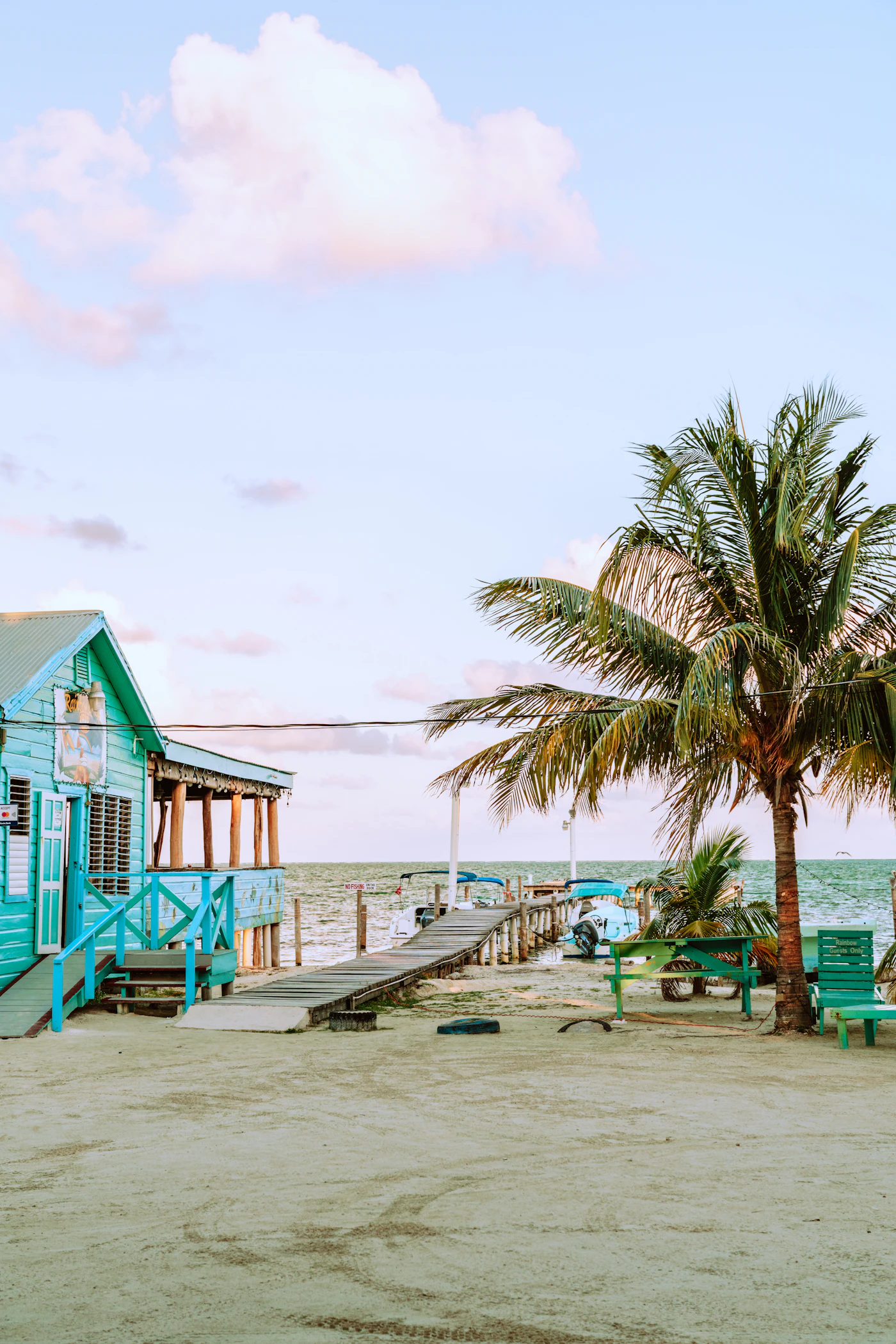 Restaurante de madera sobre el agua con lanchas en Cayo Caulker, Belice