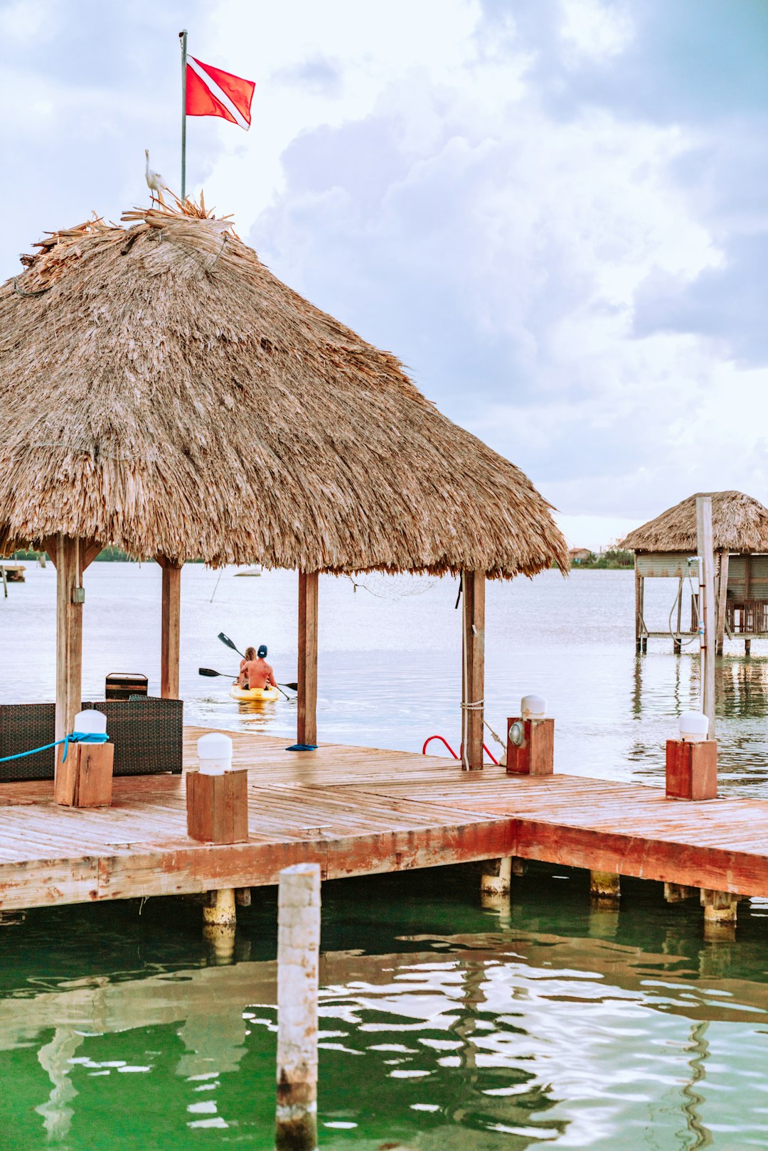 people sitting on brown wooden dock near brown nipa hut during daytime