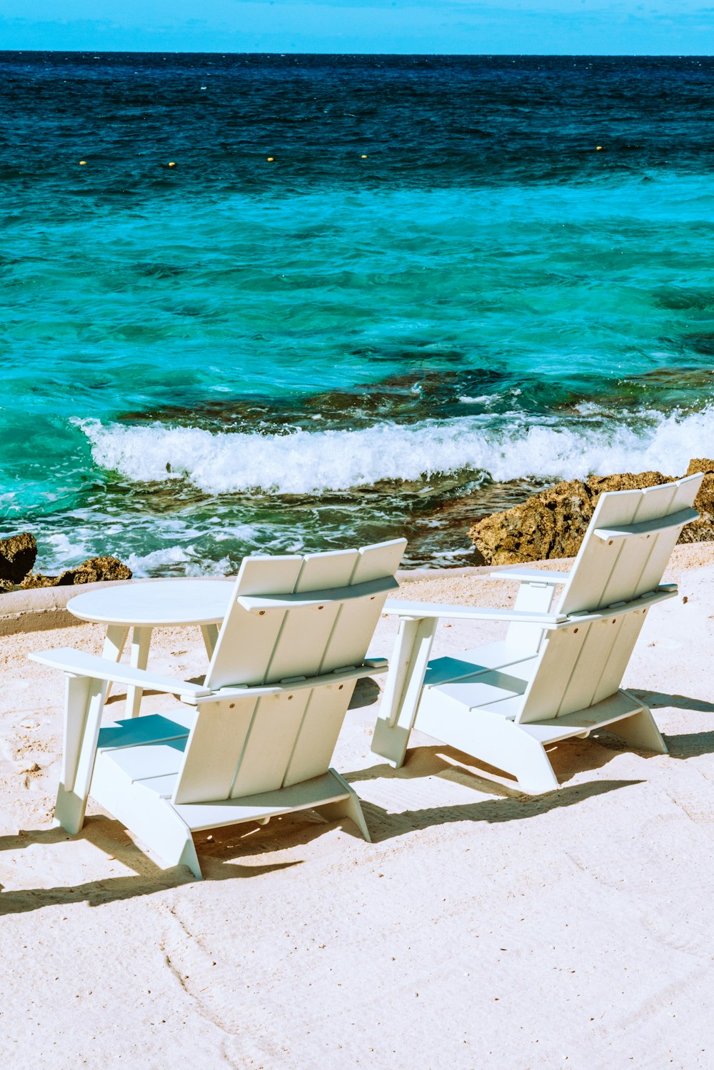white plastic armchairs on beach shore during daytime