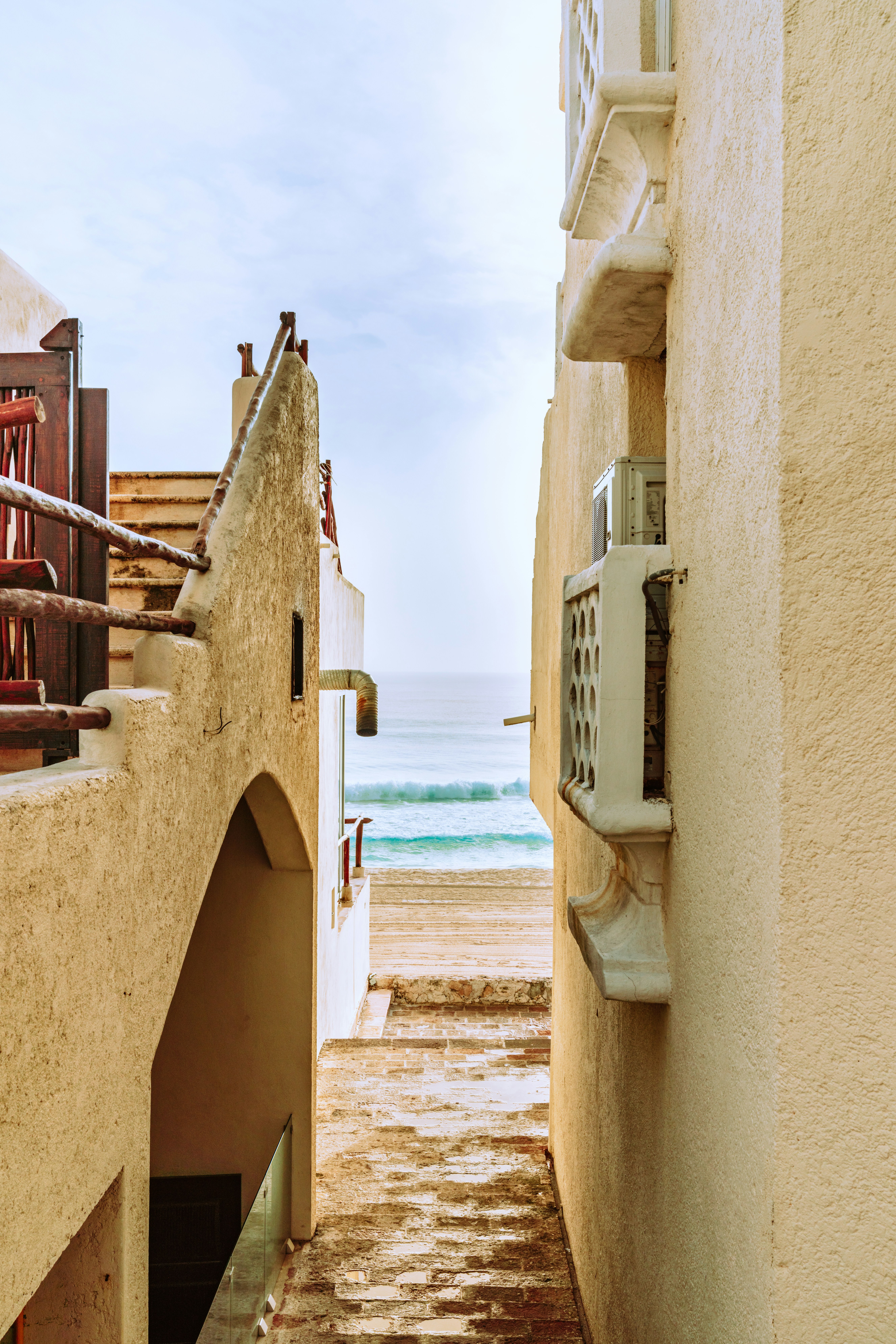 Alley walkway between two adobe buildings leading to the ocean.