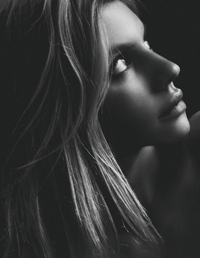 A striking black-and-white portrait capturing a thoughtful gaze against a soft charcoal grey background.