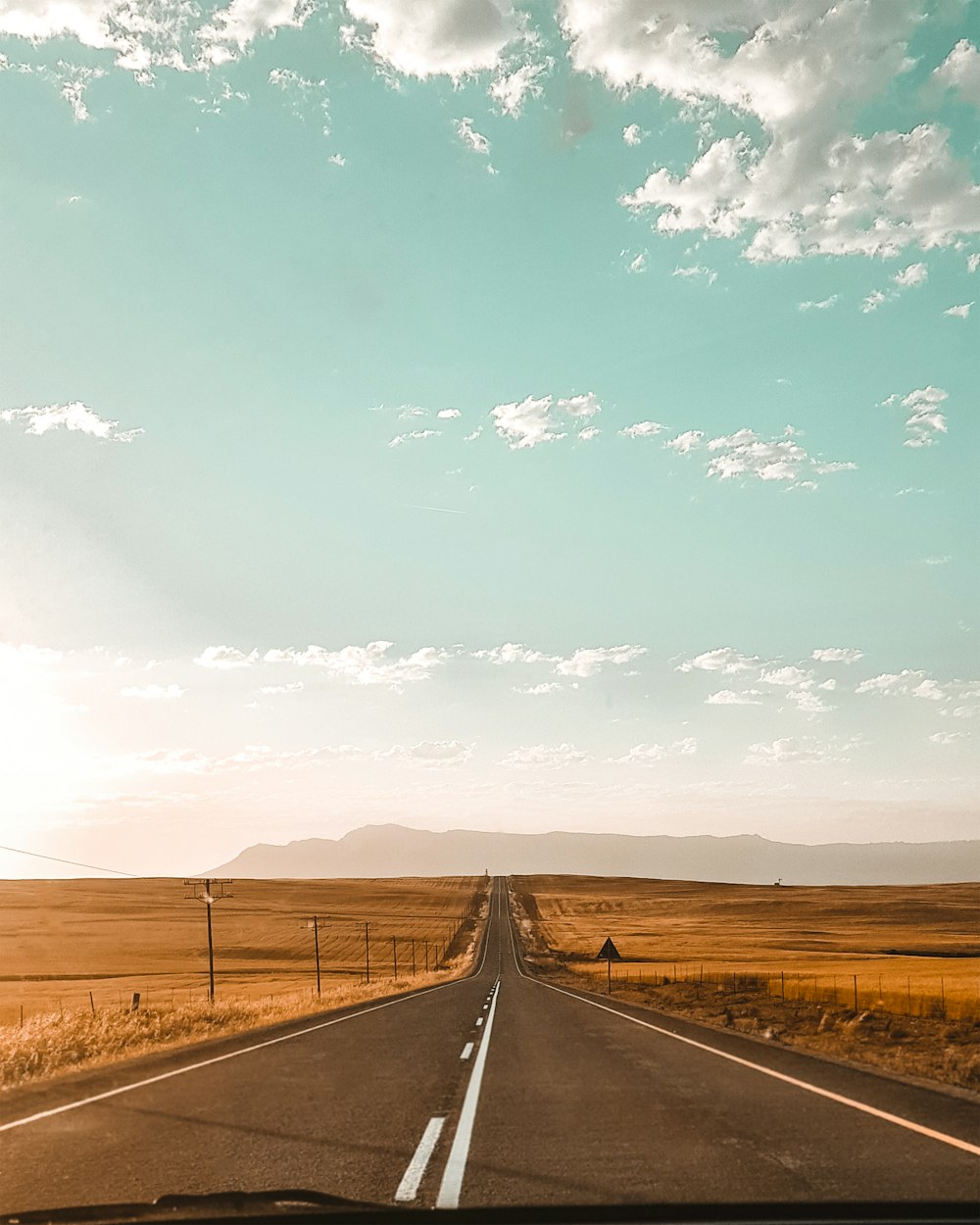 Carretera de hormigón gris entre el campo de hierba marrón bajo el cielo azul durante el día