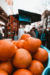 Close-up of hands exchanging fresh bergamot fruits at a bustling Calabrian market.
