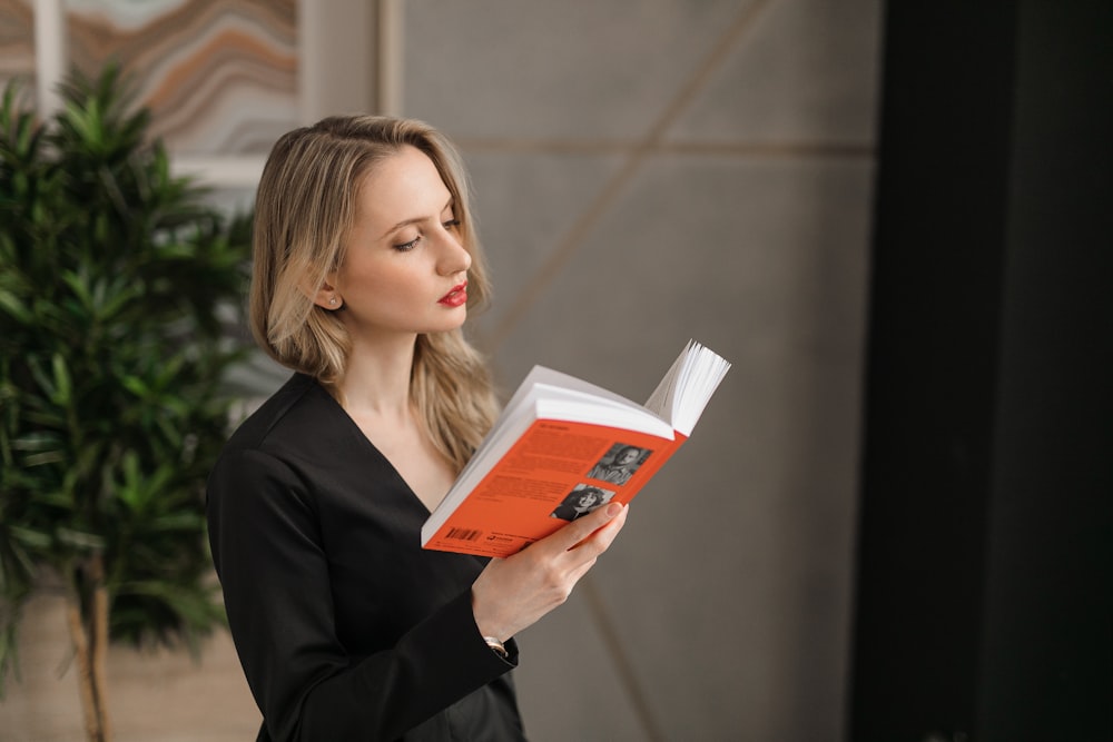 woman in black blazer holding orange book