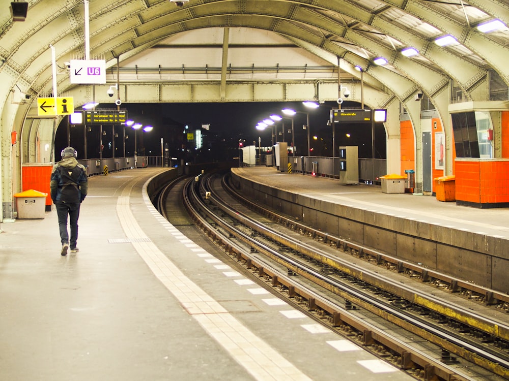 person in black jacket walking on train station