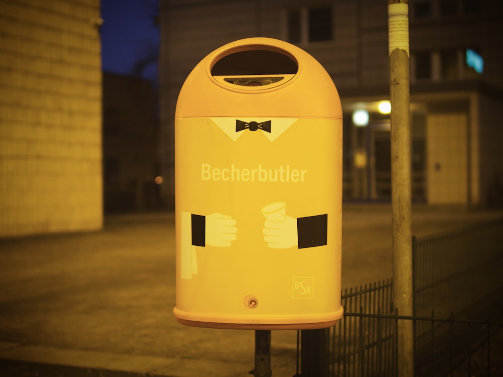 yellow trash bin on sidewalk during night time