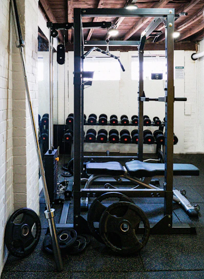A cozy home gym corner with modern fitness equipment like dumbbells, resistance bands, and a pull-up bar bathed in natural light.