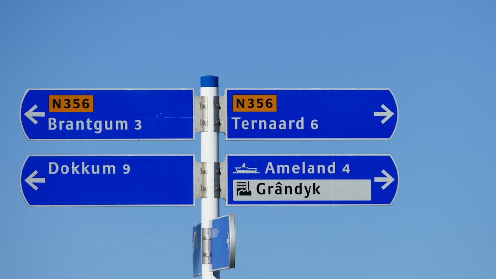 a street sign pointing in different directions against a blue sky