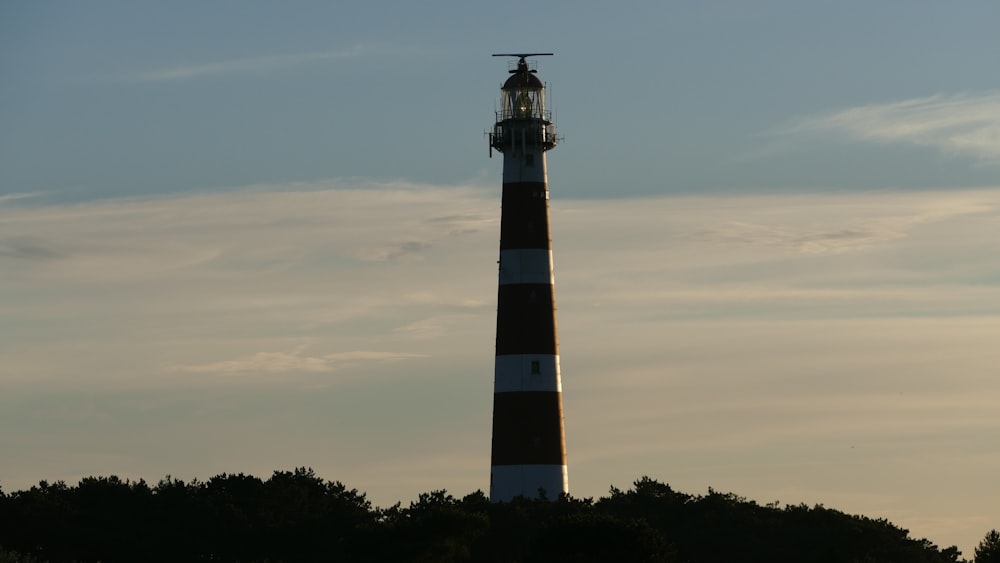 black and white lighthouse under white clouds during daytime