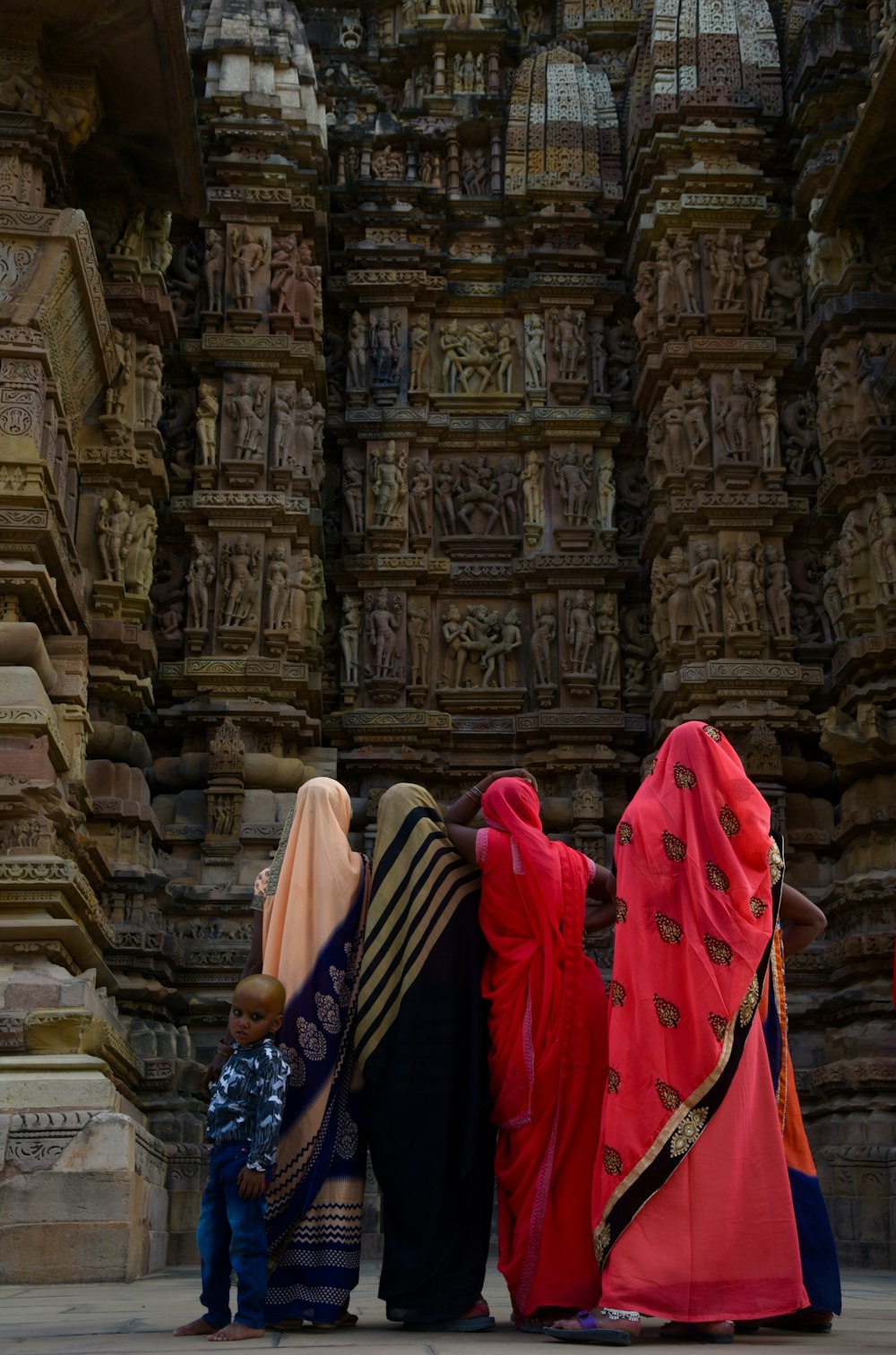 woman in blue and white sari standing near brown concrete building during daytime