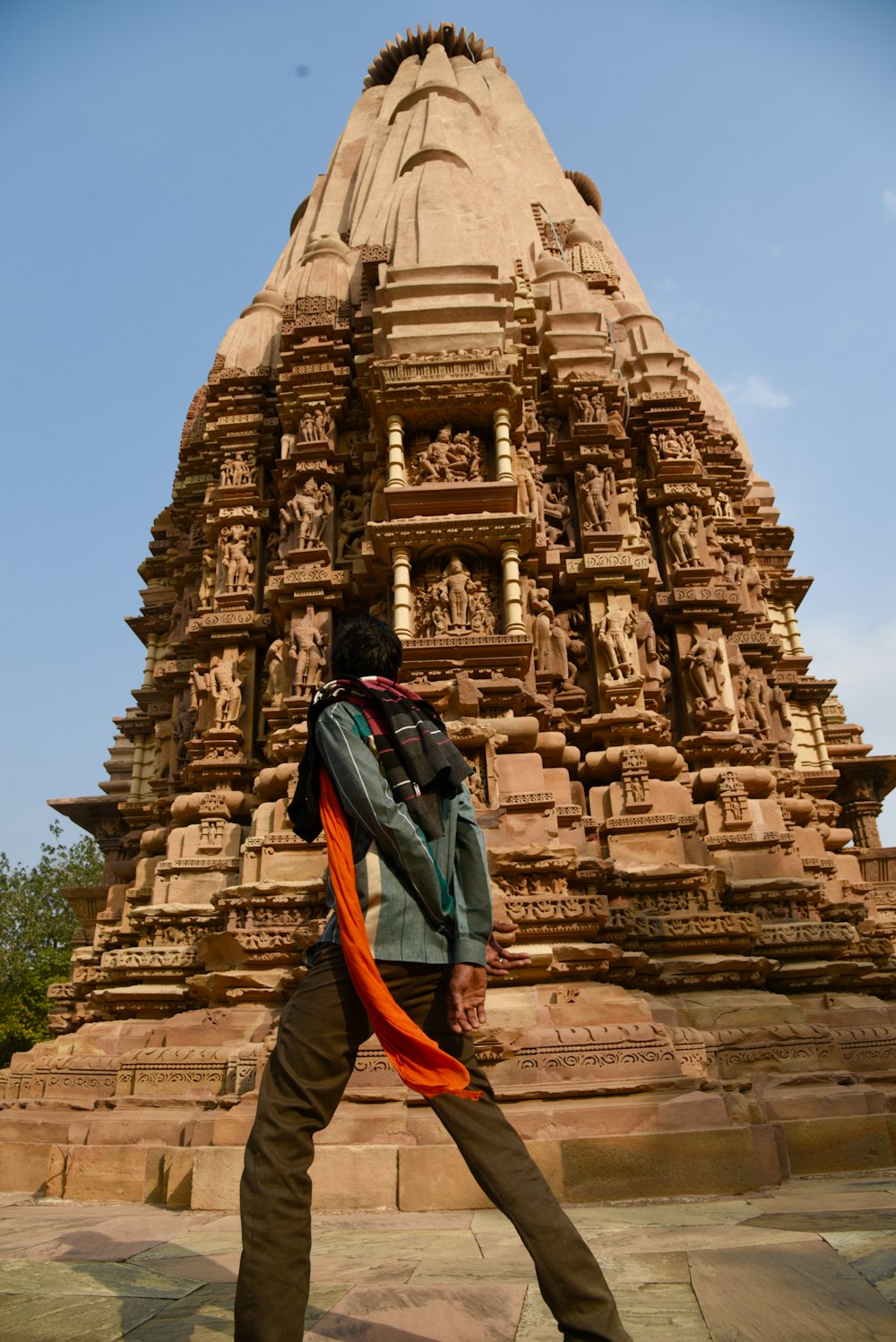 man in blue jacket and orange backpack standing in front of brown concrete building during daytime