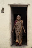 woman in yellow and brown sari standing beside white concrete wall during daytime