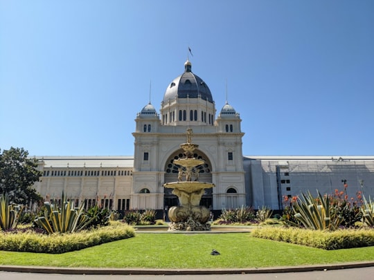 white concrete building with green grass field in Royal Exhibition Building Australia