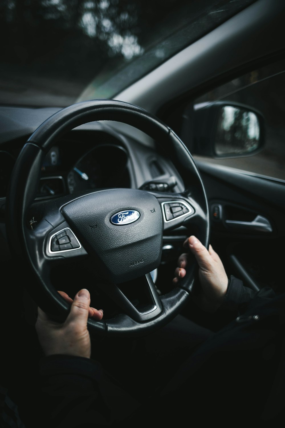 person holding black mercedes benz steering wheel