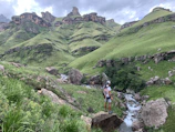 Traveler wearing a Monteverde Store hoodie standing on a mossy rock overlooking a lush valley.