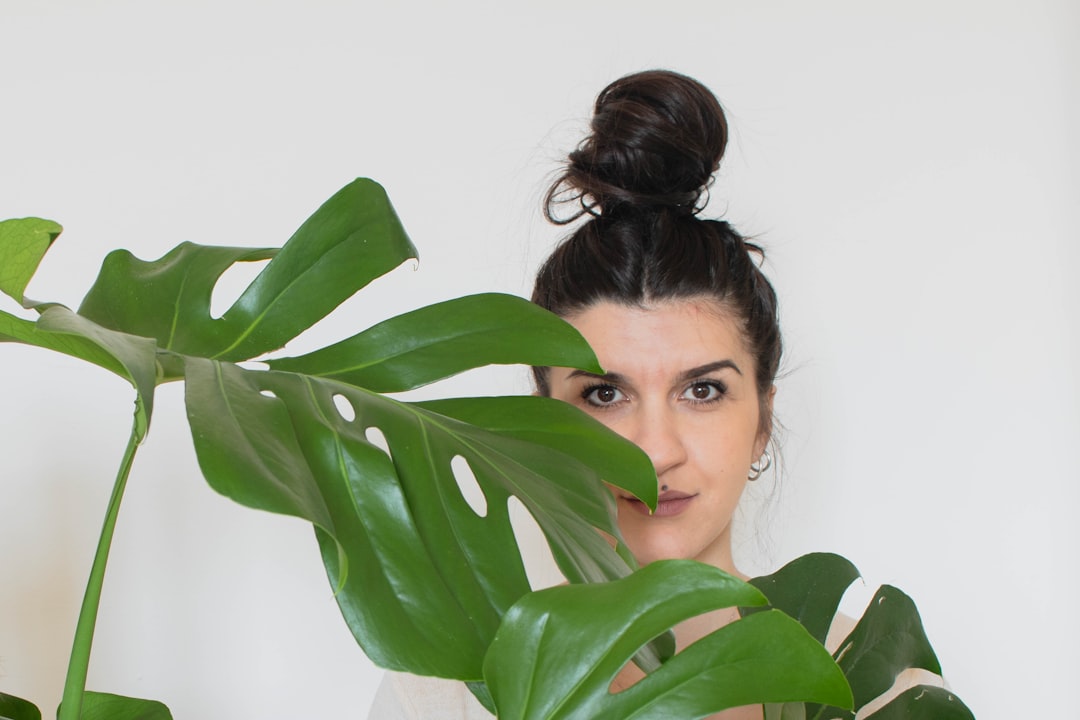 woman hiding behind green leaves