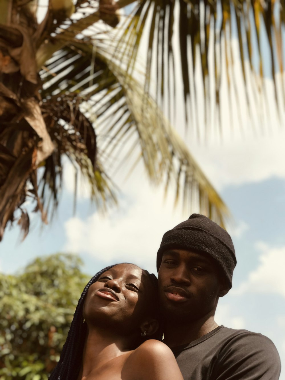 man and woman under palm tree during daytime