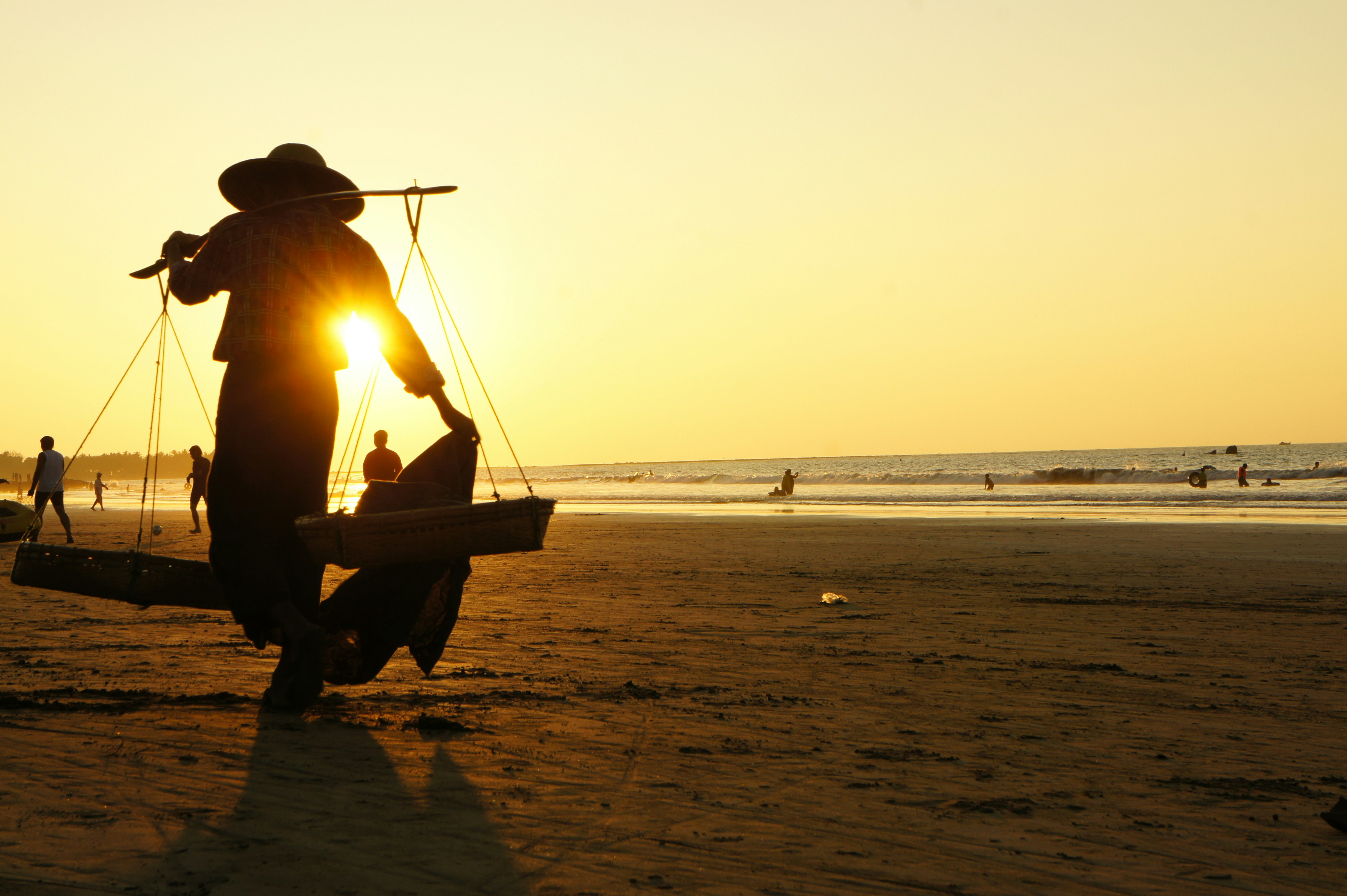 Silhouette eines Mannes, der während des Sonnenuntergangs auf dem Boot am Strand sitzt