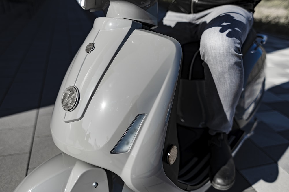 person in blue denim jeans sitting on white motorcycle