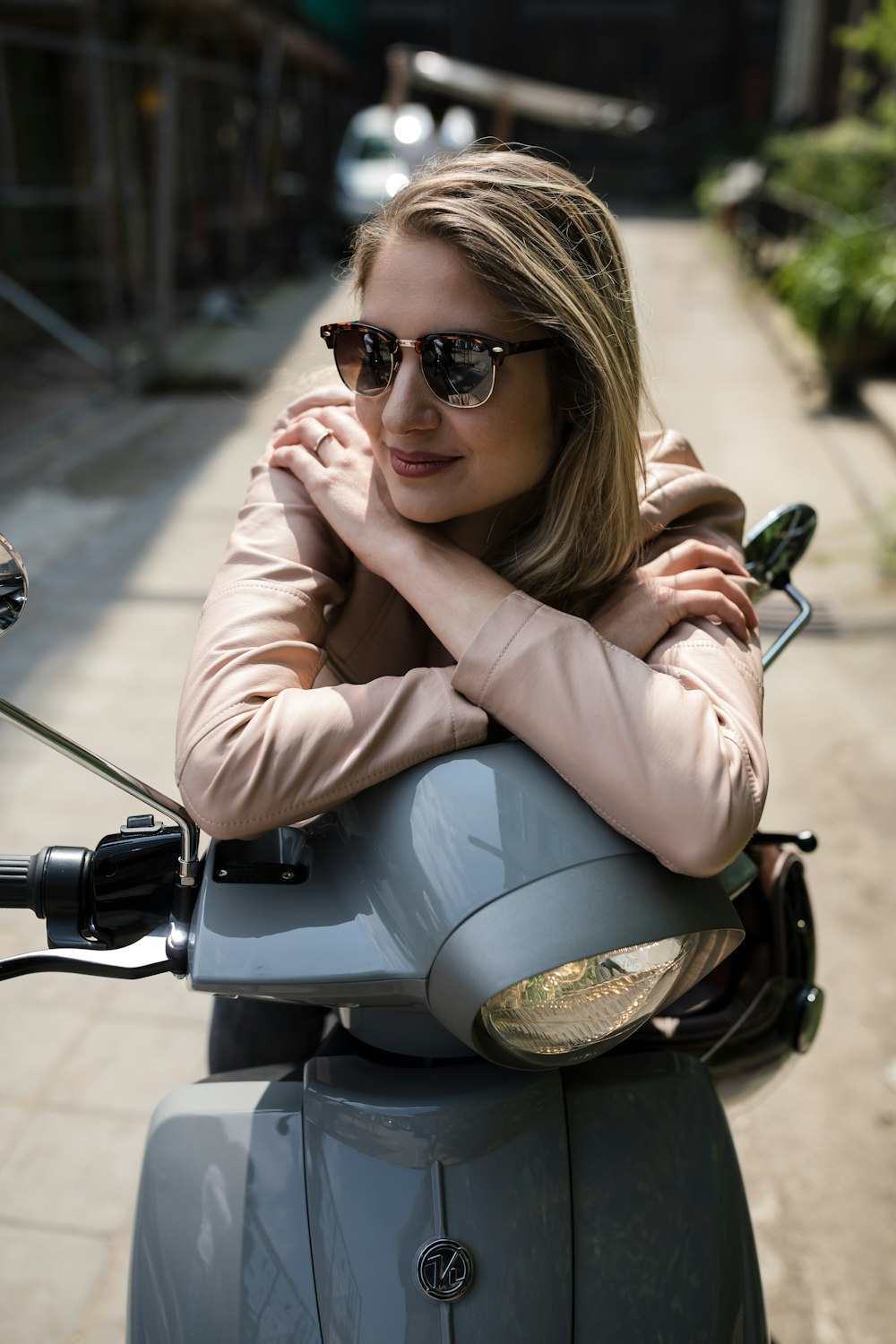 woman in brown leather jacket and black sunglasses sitting on black motorcycle