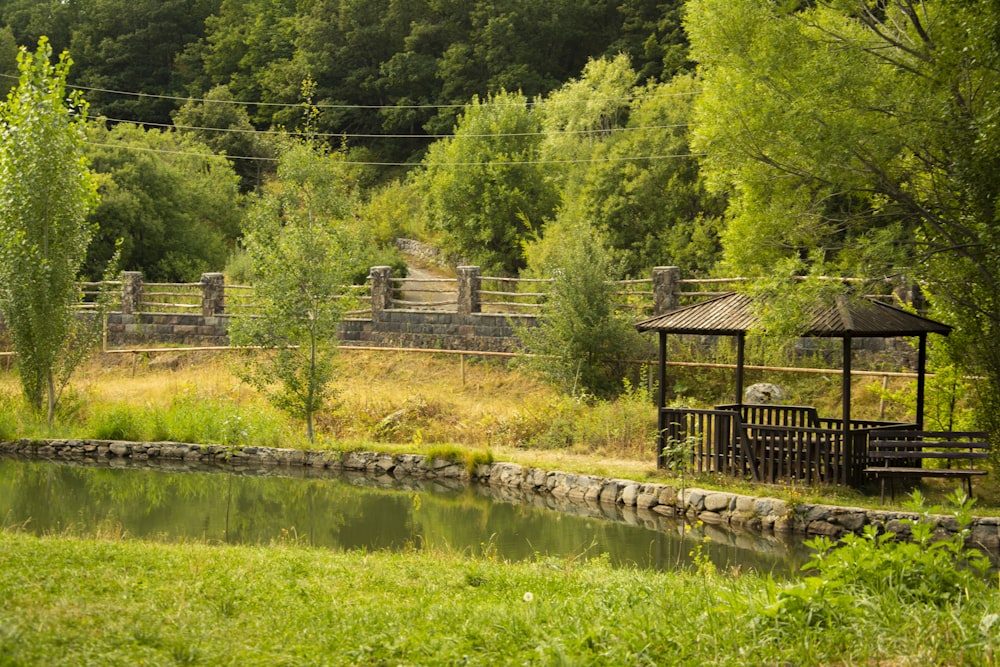 brown wooden fence near green trees and river during daytime