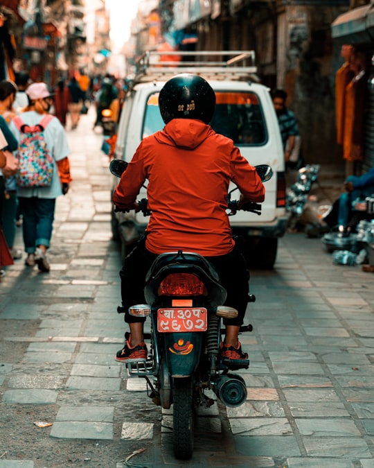 man in orange hoodie riding motorcycle in Kathmandu Nepal