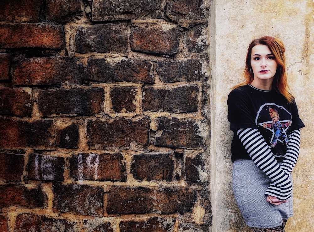 woman in black and white striped long sleeve shirt and gray denim jeans leaning on brown