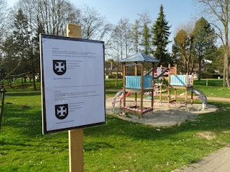 A playground safety consultant inspecting equipment with a clipboard on a sunny day.